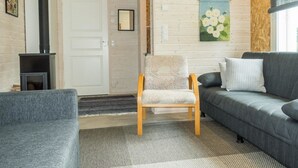 Una sala de estar acogedora con un sofá gris, una silla de madera, una chimenea y un cuadro floral en la pared.