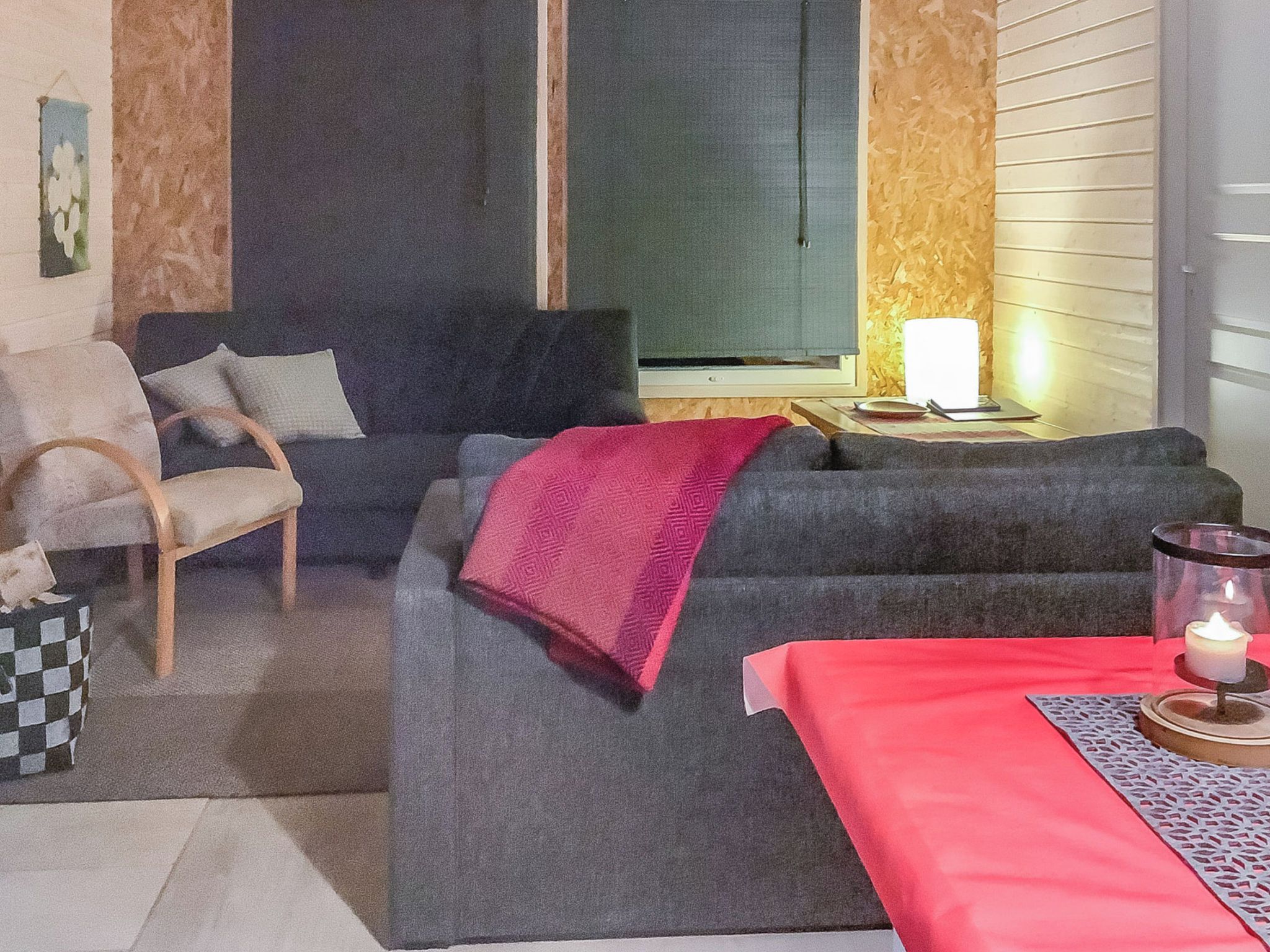 A living room with a sofa, armchair, and a table with a candle.