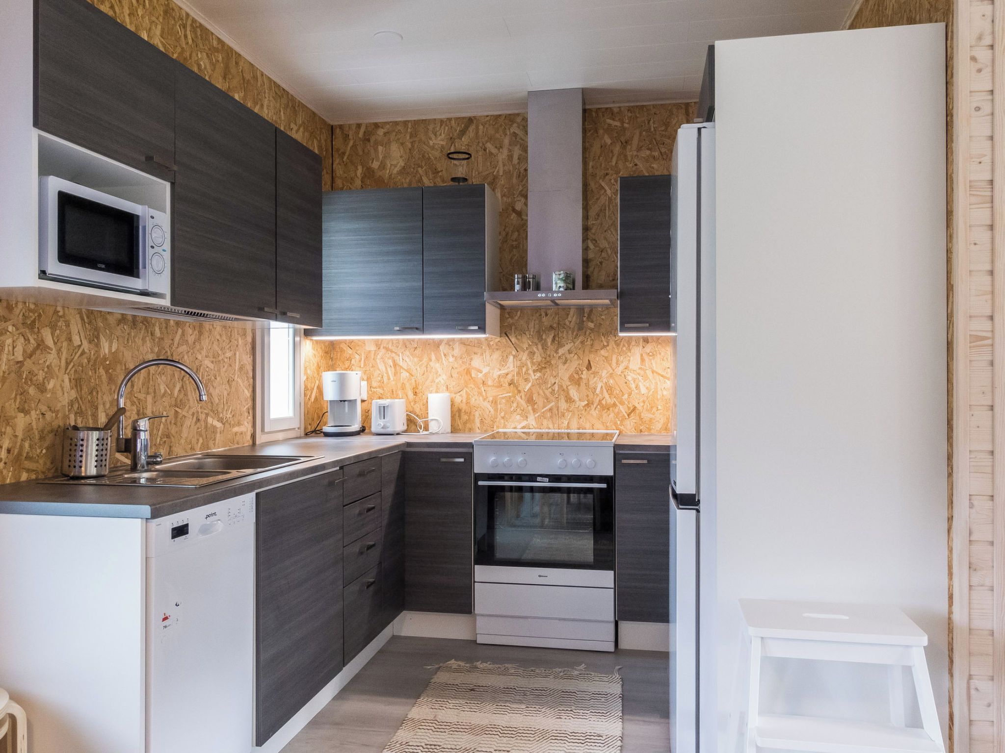 Eine kleine Küche mit Mikrowelle, Kaffeemaschine und Backofen.