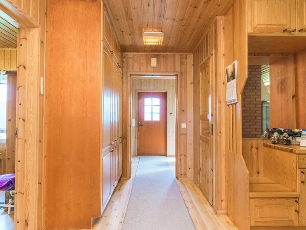 A wooden hallway with a door at the end, a window with a view, and a light fixture on the ceiling.