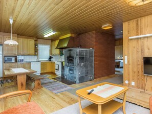A compact kitchen with wooden cabinets, a built-in oven, and a brick wall.