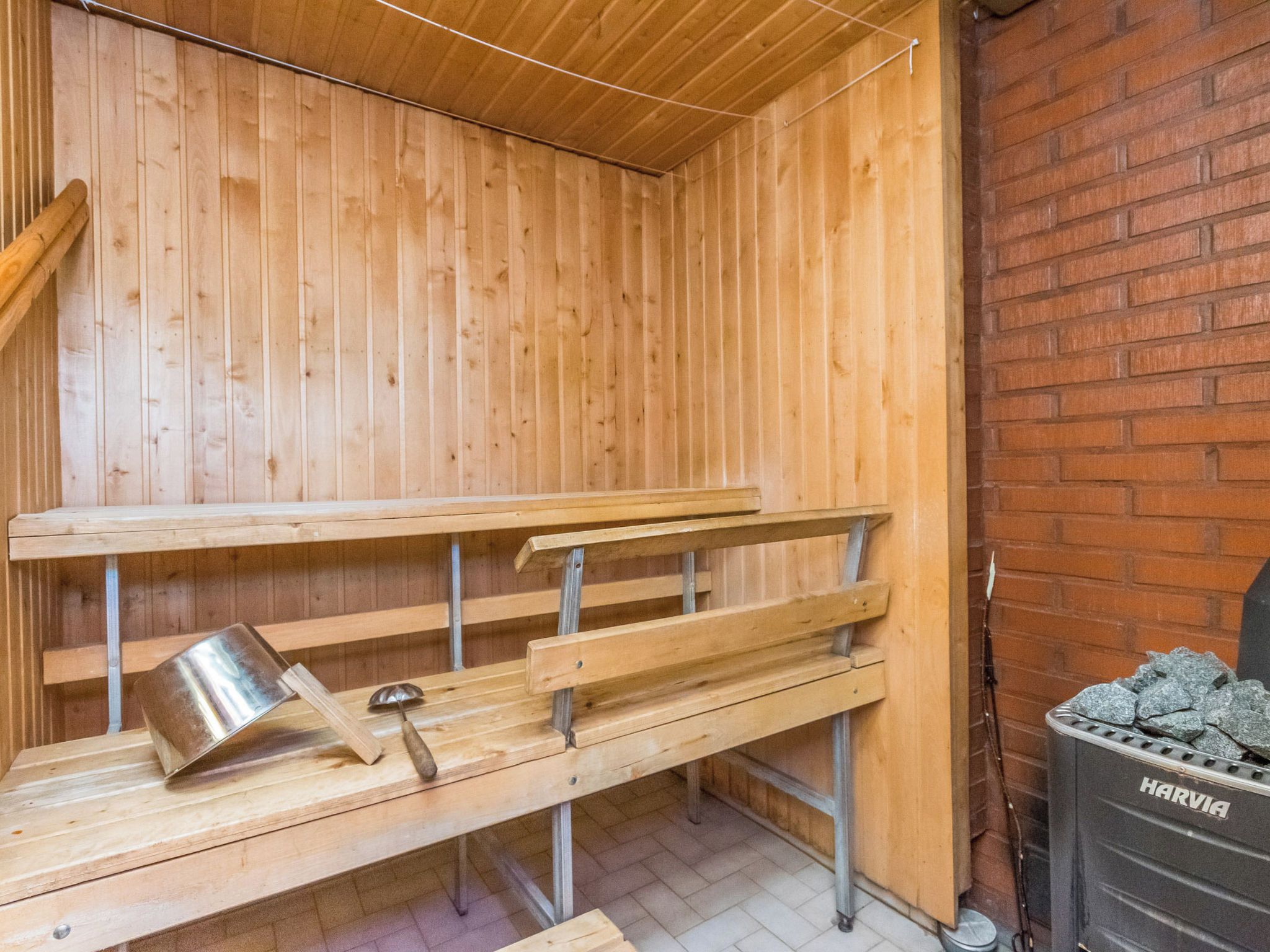 A sauna with wooden benches and a metal container, likely for water or steam.