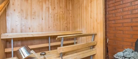 Sauna, jossa on puiset lauteet ja metallinen astia, todennäköisesti vettä tai höyryä varten.