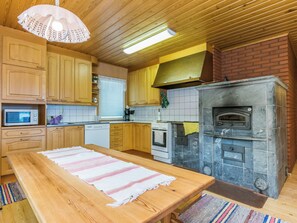 Una cocina con armarios de madera, horno empotrado, microondas y una lámpara colgante.