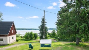 Un chalet rustique avec vue sur un lac, entouré de verdure et sous un ciel dégagé.