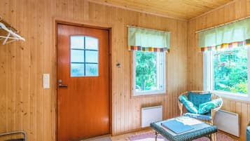 A wooden interior with a door, windows, a chair, and a radiator.