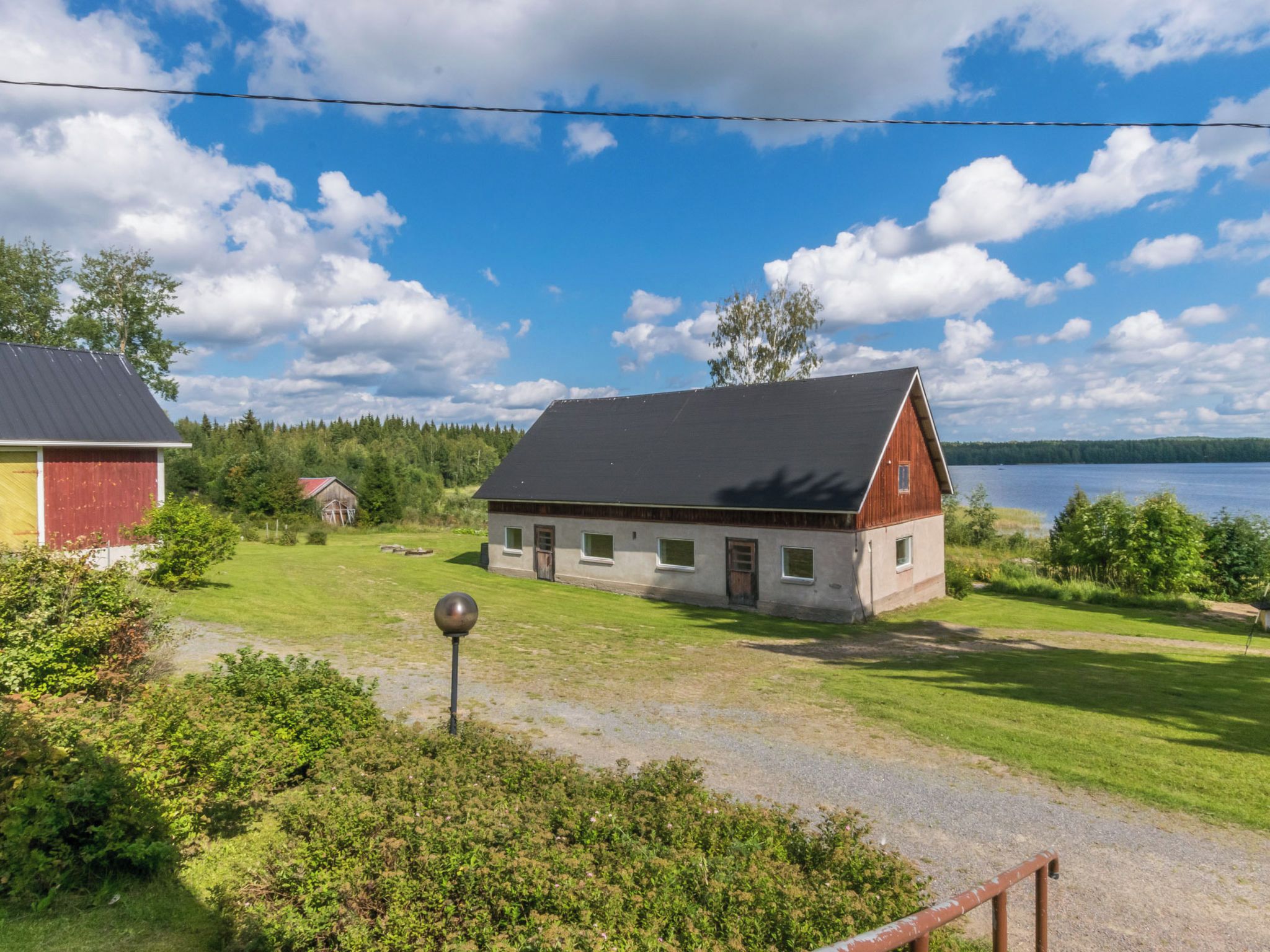 Une maison de campagne avec un toit en pente, une allée en gravier et une vue sur un lac.