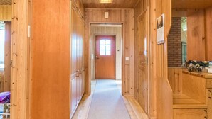 Un couloir en bois avec un sol recouvert de moquette, une porte dotée d’une fenêtre et un petit comptoir sur lequel sont posés divers objets.