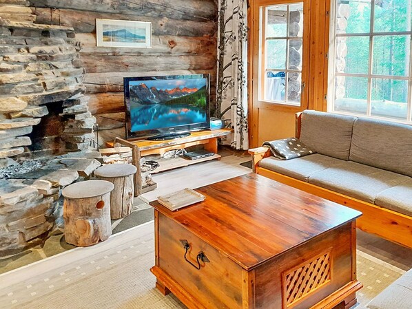 Un salon chaleureux avec une cheminée en pierre, un téléviseur, une table basse en bois et un canapé.