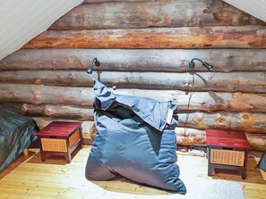 A log cabin room with a bed, two nightstands, and a hanging bag.