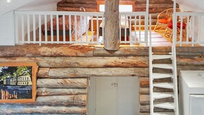 A log cabin interior with a wooden staircase, white railings, and a view of the outside. - Vacation home Rakka by Interhome (Kittilä)