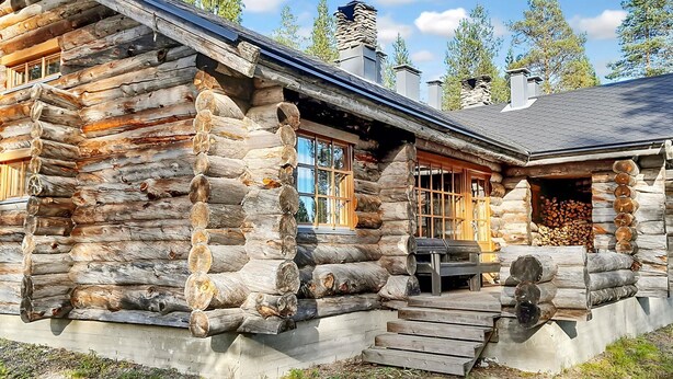 A log cabin with a stone chimney, large windows, and a wooden deck. - Vacation home Rakka by Interhome (Kittilä)