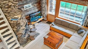 A cozy living room with a stone fireplace, a television, a sofa, and a wooden coffee table. - Vacation home Rakka by Interhome (Kittilä)