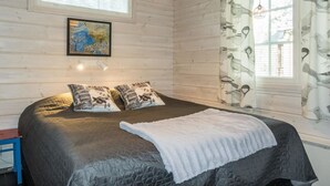 Un dormitorio con una cama grande, dos almohadas, una lámpara colgante, una ventana con cortinas y un cuadro enmarcado en la pared.