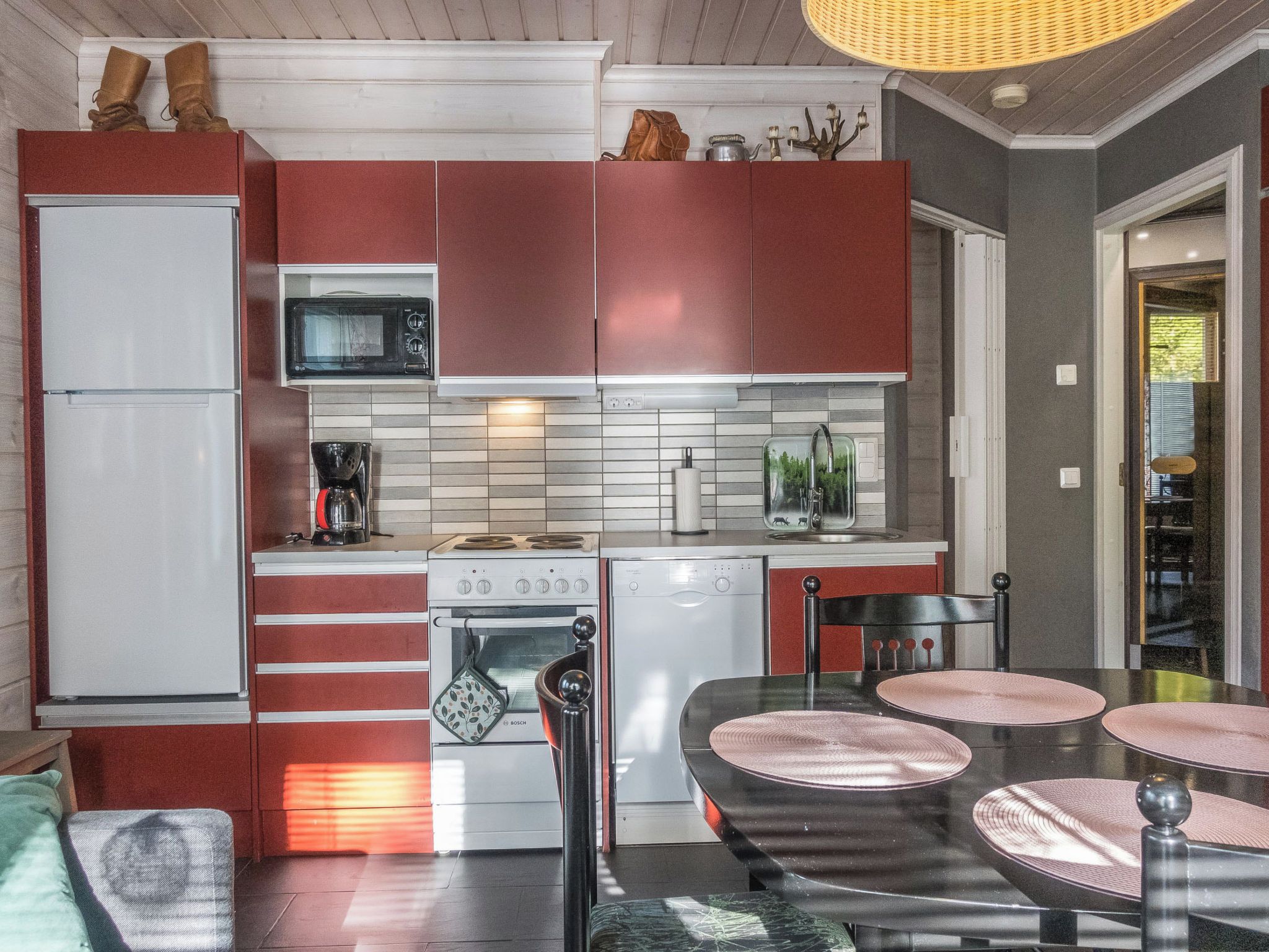 A compact kitchen with a refrigerator, microwave, stove, and dishwasher. There is a dining area with a table and chairs.