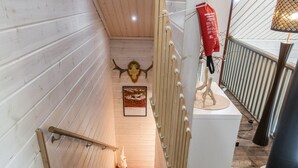 Una escalera de madera con un letrero rojo y blanco, una decoración de calavera y un cuadro en la pared.