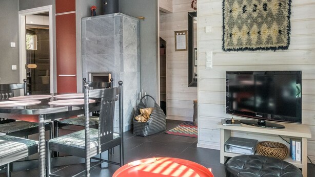 Una sala de estar moderna con chimenea, un comedor con mesa y sillas, un televisor y una alfombra estampada.