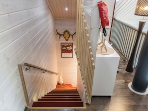 A wooden staircase with a red carpet leading to a landing.