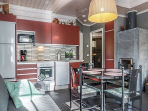 A modern kitchen with red cabinets, a Bosch oven, and a dining area with a glass table and metal chairs.
