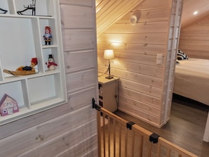Et trægulv med en seng, et natbord og en lampe.