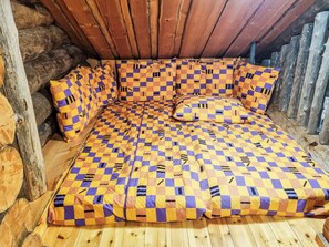 Une pièce chaleureuse, aménagée comme un chalet en bois, avec une couverture à carreaux et des murs en bois.