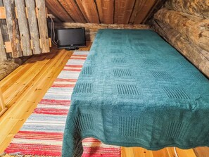 Une pièce chaleureuse avec un plancher en bois, une couverture de couleur turquoise et un téléviseur posé sur un meuble en bois.