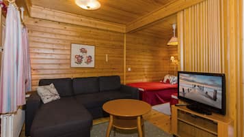 A cozy room with a sofa, a small table, a TV, and a bed.