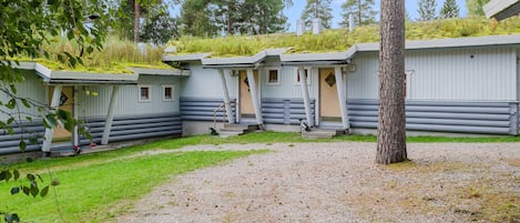 A row of log cabin-style cabins with a gravel driveway and surrounding greenery.