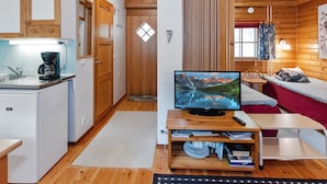 A cozy cabin interior with a kitchen, dining area, and a TV on a wooden table.