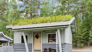 A small cabin with a porch, two chairs, and a door.
