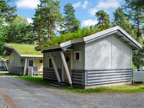 Une rangée de chalets de style rustique, construits en rondins de bois, avec une allée de gravier menant à eux.