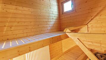 Ein Holzblock-Innenraum mit Schlafkoje, kleinem Fenster und geneigter Decke.