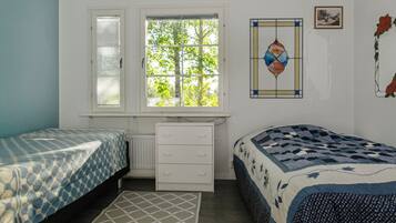 Un dormitorio con dos camas, un aparador, un radiador, una ventana con persianas y un adorno en la pared.