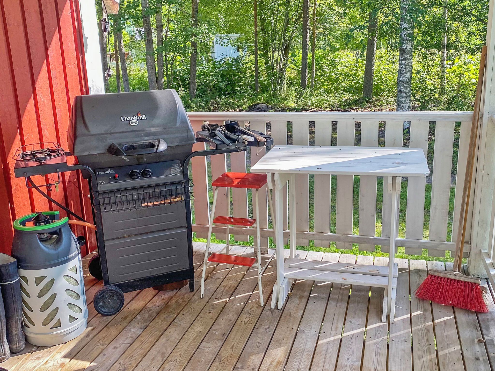 An outdoor deck with a barbecue grill, a table, and a bench.