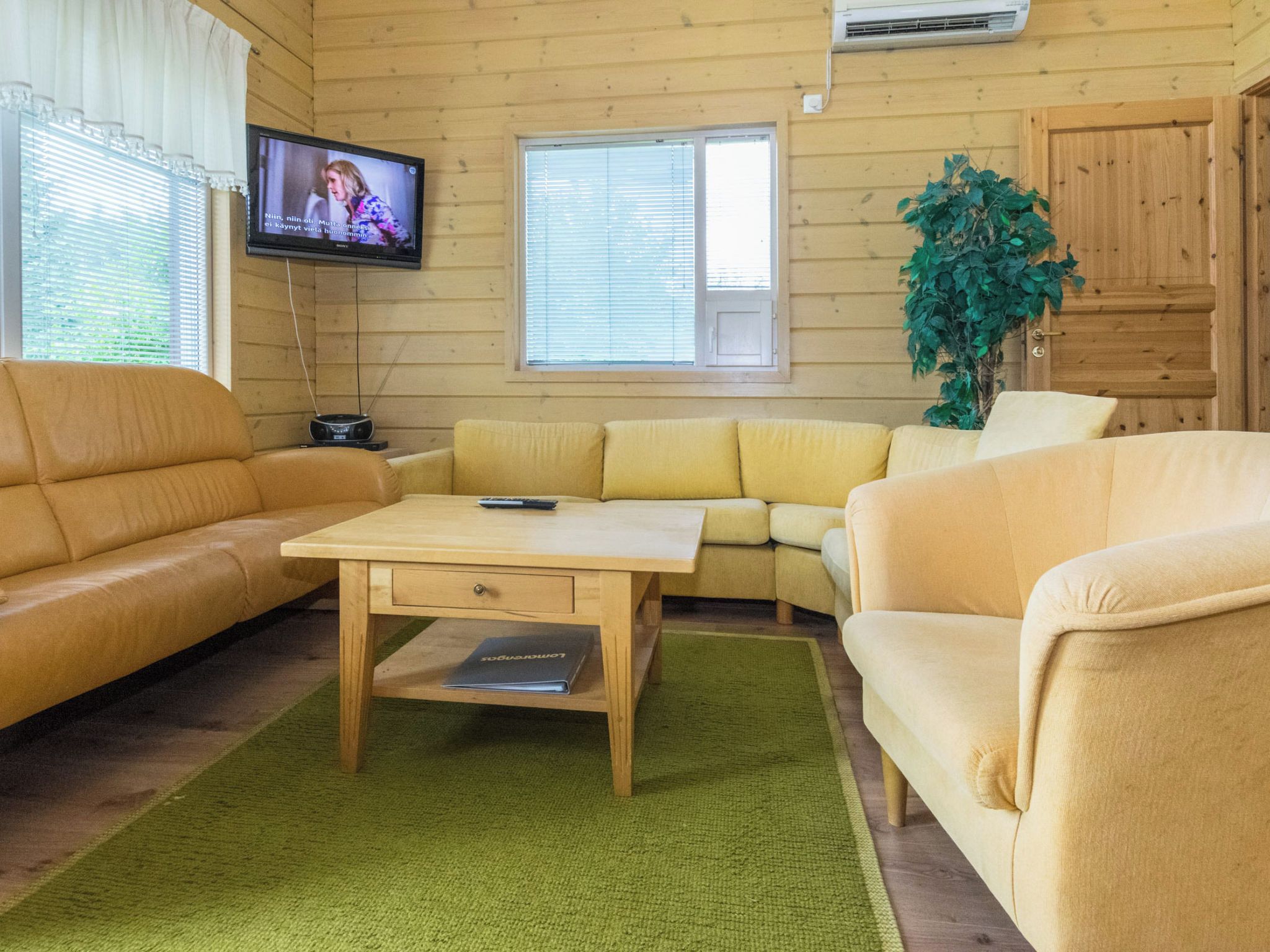 A cozy living room with a sofa set, a coffee table, and a television mounted on the wall.