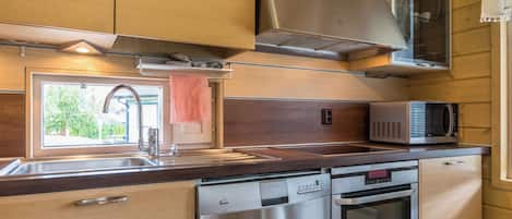 Een kleine keuken met roestvrijstalen apparatuur, een magnetron en houten kastjes.