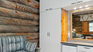 A modern kitchen with white cabinets, a wooden wall, and a built-in refrigerator. - Raahenmaja by Interhome (Inari)