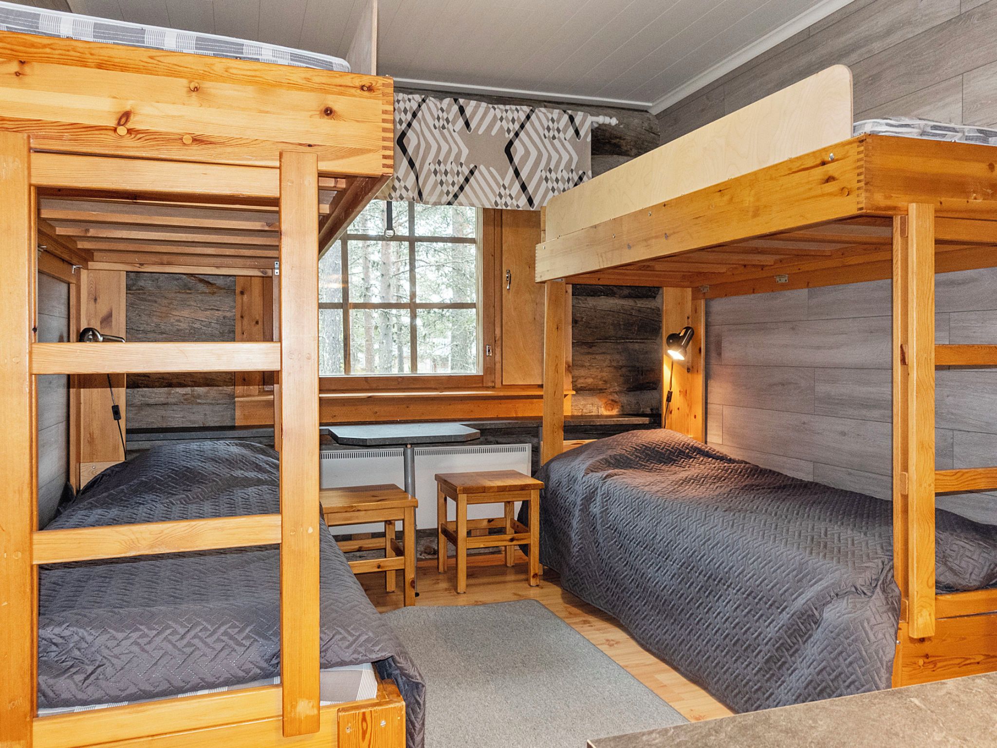 A compact cabin with bunk beds, a small kitchenette, and a window with a view of trees.