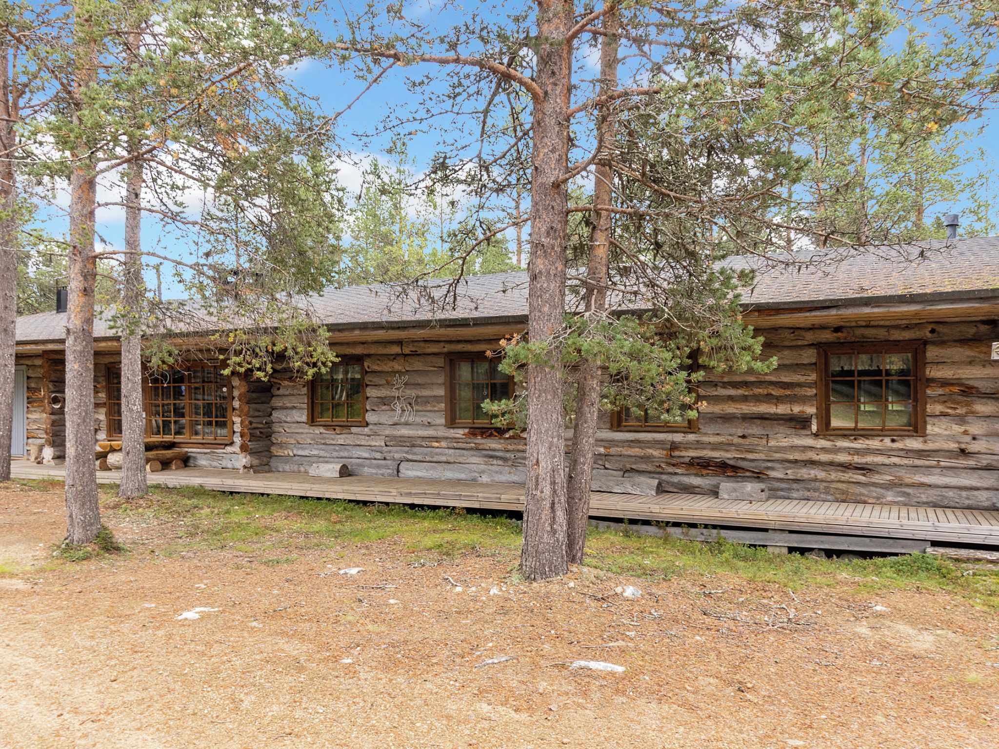 A rustic log cabin with a wooden deck and a clear sky.