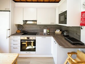 A compact kitchen with white cabinets, a built-in oven, a microwave, and a sink.