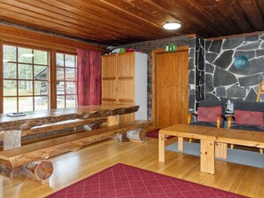 A wooden interior with a stone wall, a wooden bench, a table, and a door marked with an arrow. - Raahenmaja by Interhome (Inari)