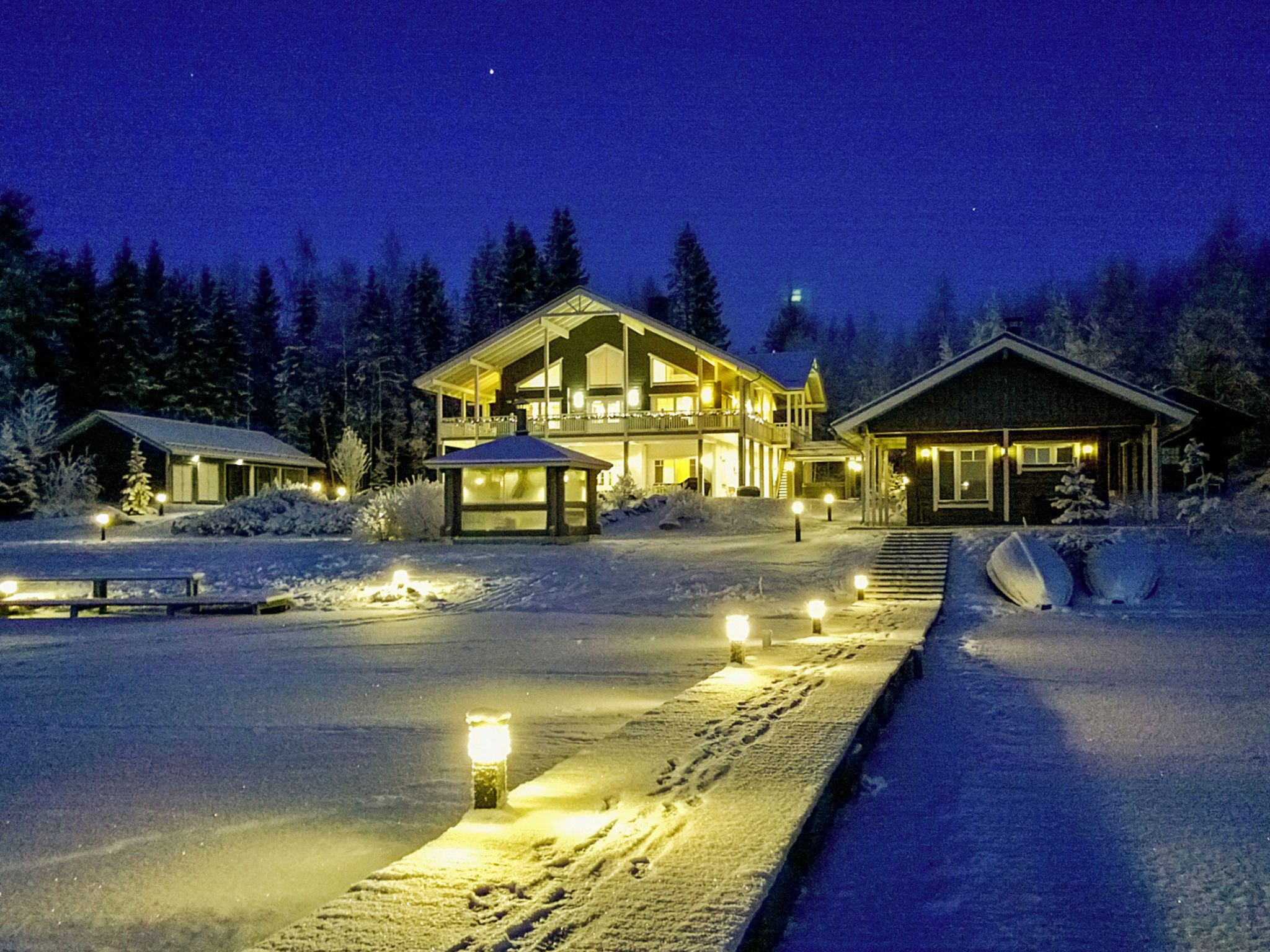 A snow-covered landscape with a large lodge featuring multiple levels and a prominent entrance.