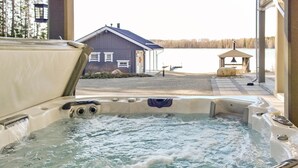 A hot tub with a view of a house and a body of water.