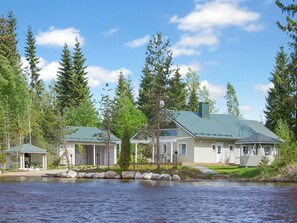 A lakeside cabin with a covered porch, a small dock, and a view of the surrounding forest. - Riemurahi by Interhome (Pertunmaa)