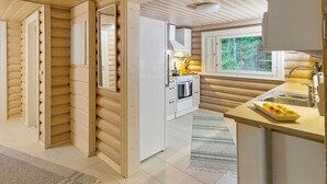 A modern log cabin interior with a kitchen, a dining area, and a large window offering a view of the outdoors. - Riemurahi by Interhome (Pertunmaa)