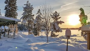 A snow-covered landscape with a mailbox, trees, and a building in the background. - Riemurahi by Interhome (Pertunmaa)