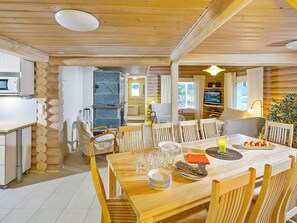 A cozy wooden interior with a dining area, kitchen, and a cozy seating area with a TV. - Riemurahi by Interhome (Pertunmaa)