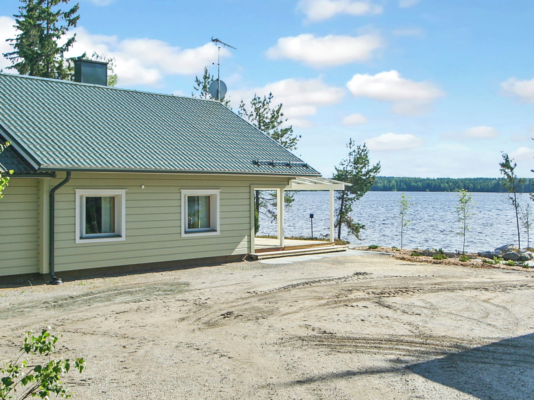A house with a covered porch, a gravel driveway, and a view of a lake.
