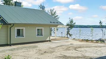 A house with a covered porch, a gravel driveway, and a view of a lake.