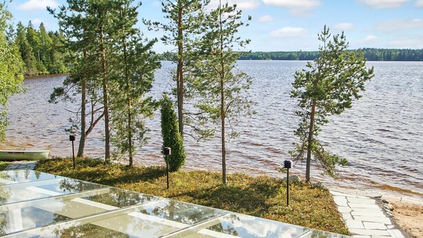 A glass-enclosed outdoor area with a view of a lake and trees. - Riemurahi by Interhome (Pertunmaa)